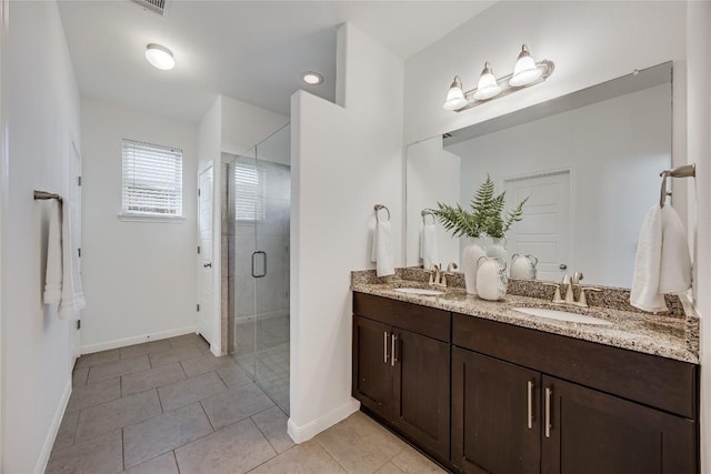 full bath featuring double vanity, a stall shower, tile patterned floors, and a sink