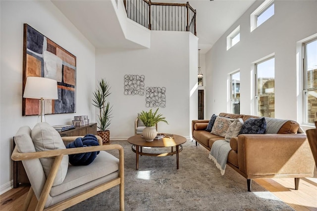 living area featuring a high ceiling, wood finished floors, and baseboards