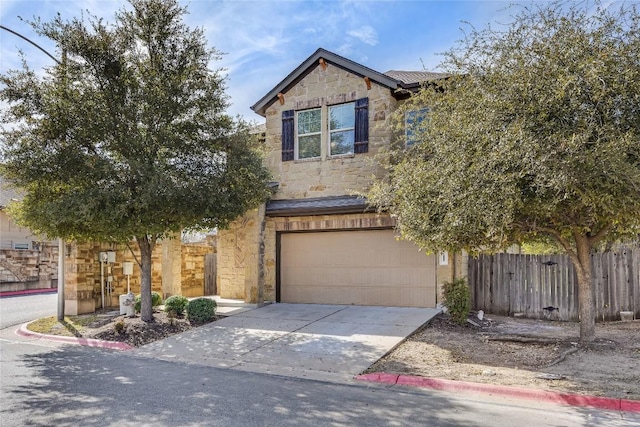 traditional-style home with stone siding, an attached garage, concrete driveway, and fence