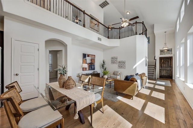 dining space with arched walkways, light wood-style floors, visible vents, and ceiling fan