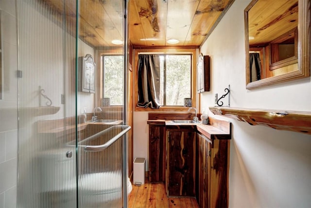 bathroom with wooden ceiling, wood finished floors, a stall shower, and vanity