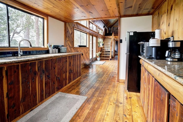 kitchen featuring a sink, a wealth of natural light, light wood-style floors, and wooden ceiling