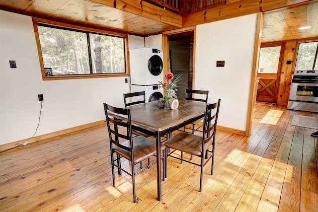 dining area with wooden ceiling, light wood-style flooring, baseboards, and stacked washer and clothes dryer