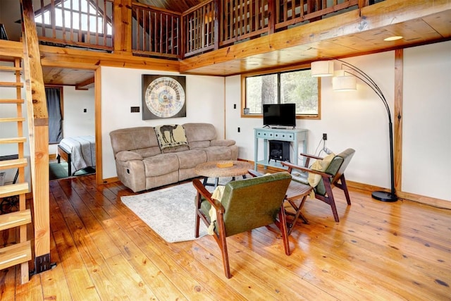 living area with baseboards, hardwood / wood-style floors, and a towering ceiling