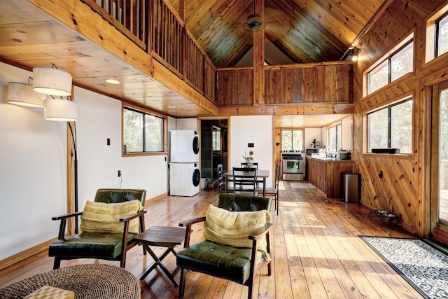 living room featuring wooden walls, wood ceiling, light wood-type flooring, and high vaulted ceiling