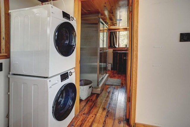 washroom featuring hardwood / wood-style flooring, laundry area, and stacked washing maching and dryer