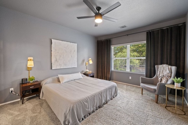 carpeted bedroom with visible vents, baseboards, a textured ceiling, and ceiling fan