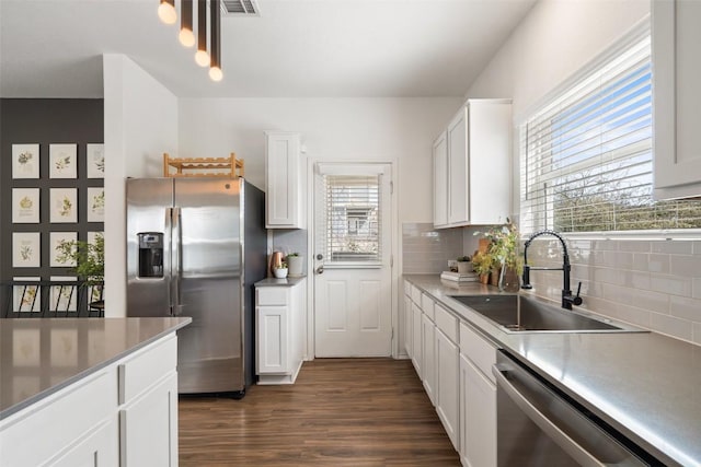 kitchen featuring dark wood-style floors, a sink, decorative backsplash, stainless steel appliances, and white cabinets