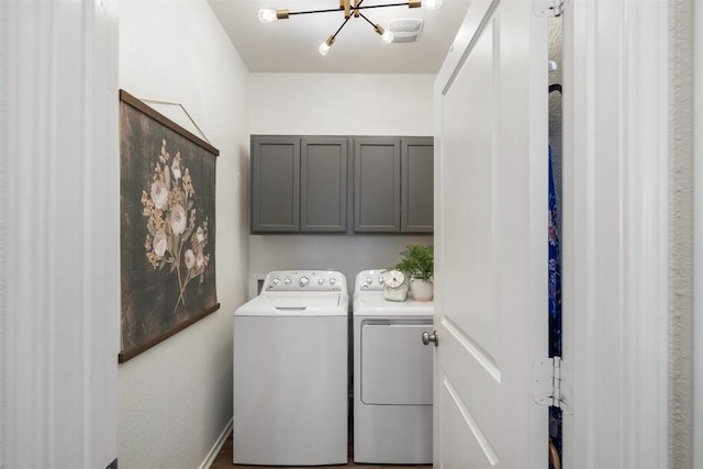 washroom featuring washing machine and dryer, a notable chandelier, and cabinet space