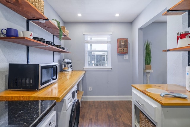 interior space with baseboards, open shelves, washer / dryer, dark wood-style flooring, and stainless steel microwave