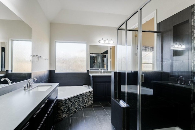 bathroom featuring tile patterned floors, a stall shower, a garden tub, and a sink