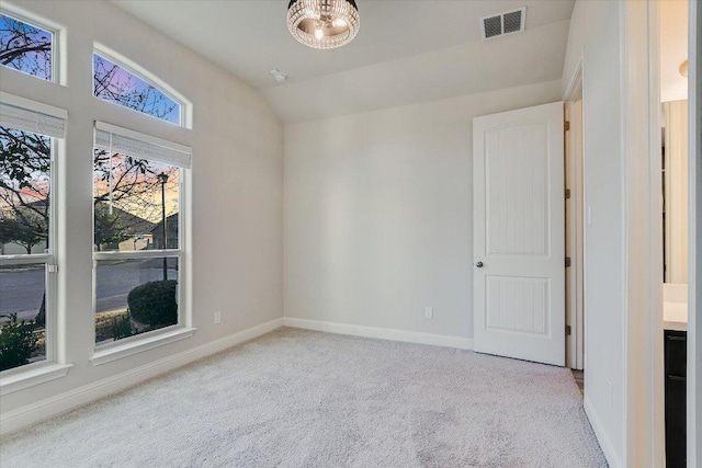 unfurnished room with visible vents, lofted ceiling, an inviting chandelier, carpet flooring, and baseboards