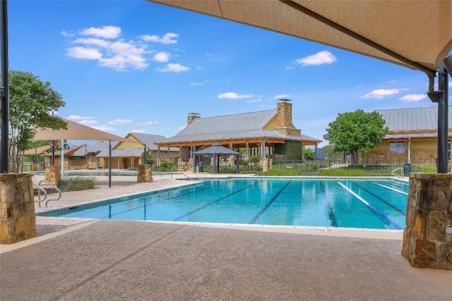 pool with a gazebo, a patio, and fence