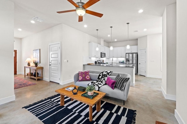 living area featuring recessed lighting, a ceiling fan, baseboards, and finished concrete floors