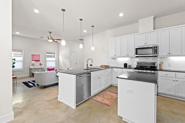 kitchen featuring finished concrete flooring, a peninsula, a sink, stainless steel appliances, and tasteful backsplash