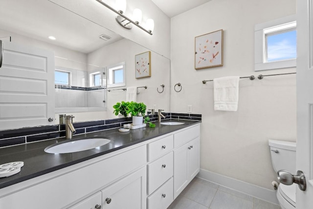 full bathroom with toilet, a healthy amount of sunlight, and a sink