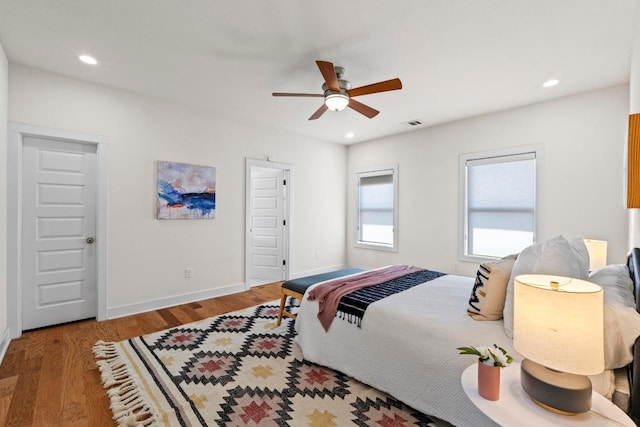 bedroom featuring a ceiling fan, visible vents, wood finished floors, baseboards, and recessed lighting