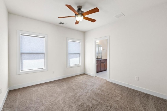 unfurnished room with light carpet, visible vents, baseboards, and a ceiling fan