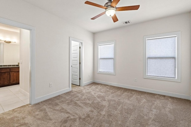 unfurnished bedroom with light tile patterned floors, baseboards, visible vents, ensuite bath, and light carpet