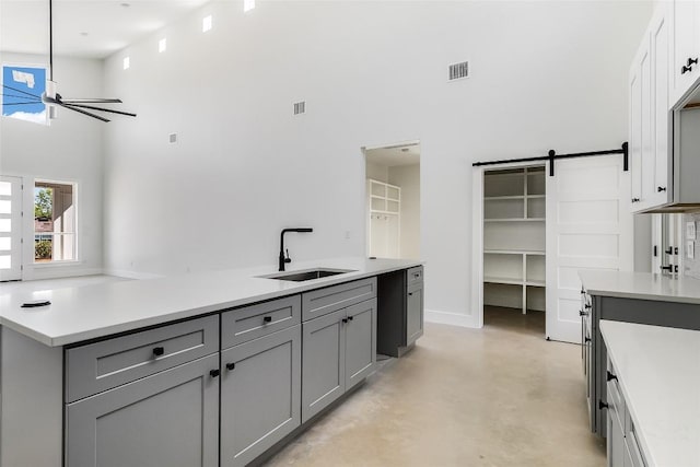 kitchen featuring a sink, gray cabinets, finished concrete floors, a towering ceiling, and visible vents
