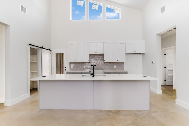 kitchen with visible vents, baseboards, a high ceiling, a sink, and backsplash