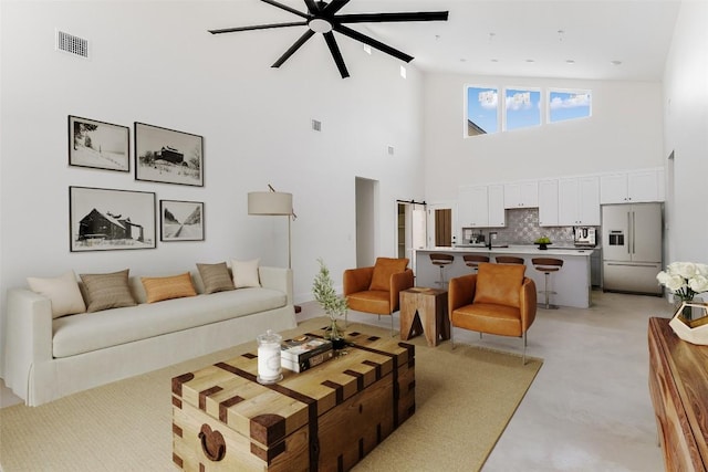 living room featuring a high ceiling, ceiling fan, and visible vents