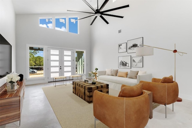 living area with ceiling fan, french doors, visible vents, a towering ceiling, and concrete flooring