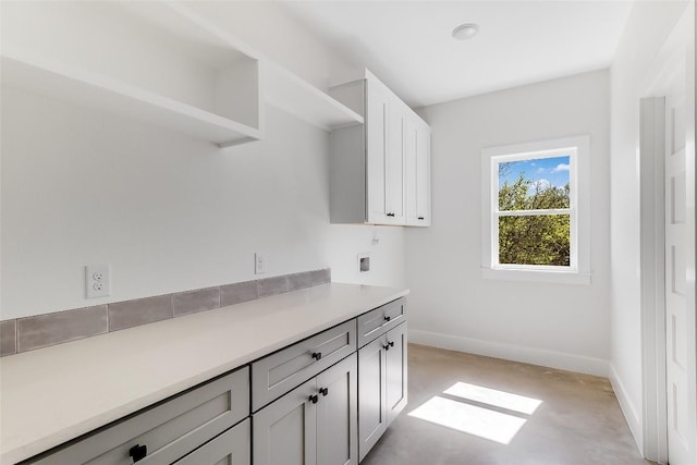 washroom with baseboards, washer hookup, and cabinet space