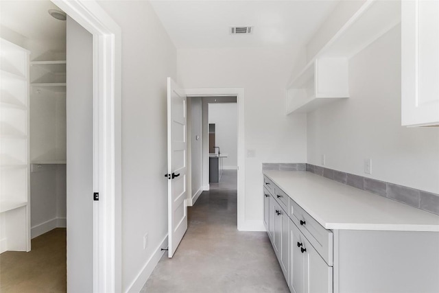 interior space featuring baseboards, visible vents, and concrete floors