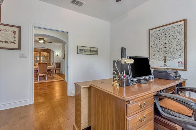 office space with wood finished floors, visible vents, baseboards, arched walkways, and ceiling fan