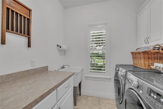 clothes washing area with light tile patterned flooring, cabinet space, baseboards, and separate washer and dryer