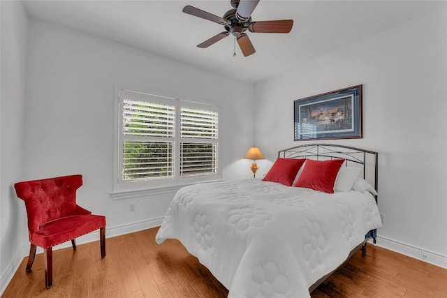 bedroom with a ceiling fan, wood finished floors, and baseboards