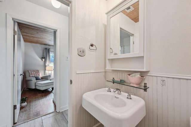 bathroom featuring a sink, a wainscoted wall, visible vents, and wood finished floors