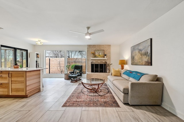 living room featuring a brick fireplace, baseboards, and a ceiling fan