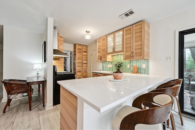 kitchen featuring black gas range oven, visible vents, glass insert cabinets, decorative backsplash, and a peninsula