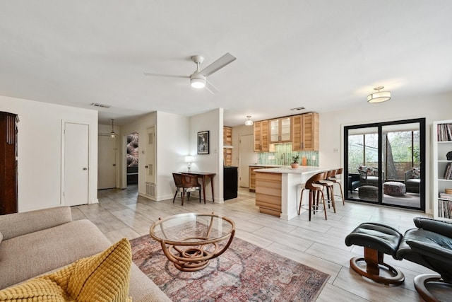 living area featuring a ceiling fan, visible vents, and baseboards