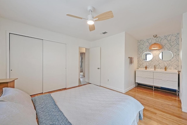 bedroom with light wood-type flooring, visible vents, a closet, baseboards, and ceiling fan