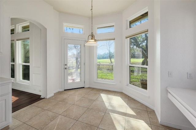 interior space with a wealth of natural light, baseboards, and light tile patterned floors