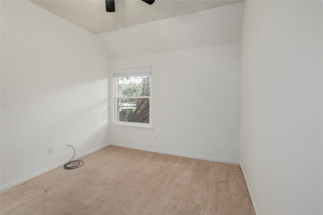 empty room featuring light colored carpet, baseboards, lofted ceiling, and a ceiling fan