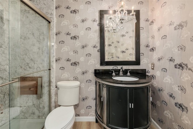 bathroom featuring a notable chandelier, toilet, a shower stall, baseboards, and vanity