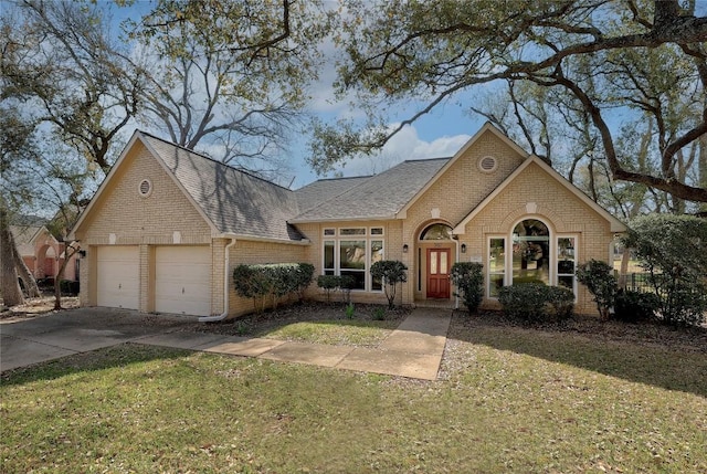 view of front facade with roof with shingles, concrete driveway, a front lawn, a garage, and brick siding