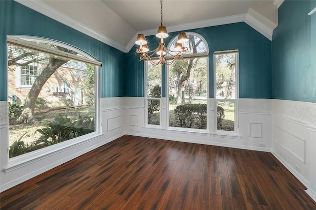 unfurnished dining area with a chandelier, dark wood-style floors, vaulted ceiling, and a wainscoted wall