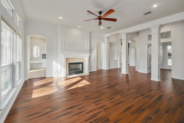 unfurnished living room with a wealth of natural light, visible vents, a fireplace with flush hearth, and a ceiling fan