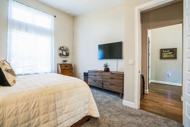 bedroom with dark wood-type flooring, baseboards, and dark colored carpet