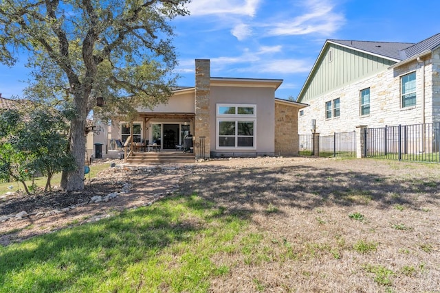 rear view of house featuring a lawn, a deck, a chimney, and fence