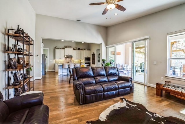 living room featuring a ceiling fan, visible vents, baseboards, recessed lighting, and wood-type flooring