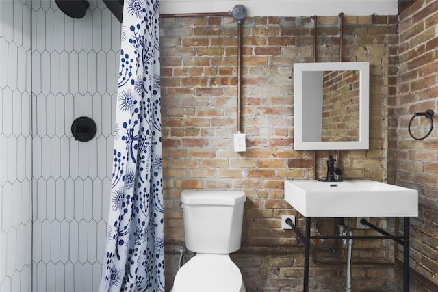 full bath featuring a tile shower, brick wall, and toilet