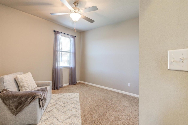 sitting room with ceiling fan, baseboards, and light carpet