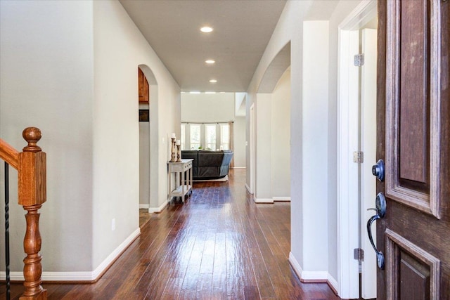 entrance foyer featuring arched walkways, dark wood finished floors, stairs, and baseboards