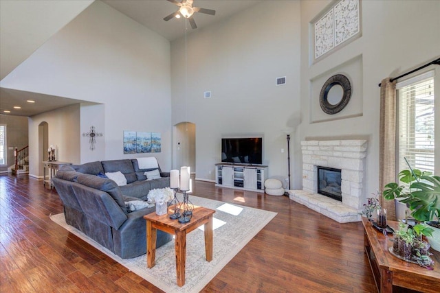 living area with a ceiling fan, dark wood-style floors, visible vents, and arched walkways